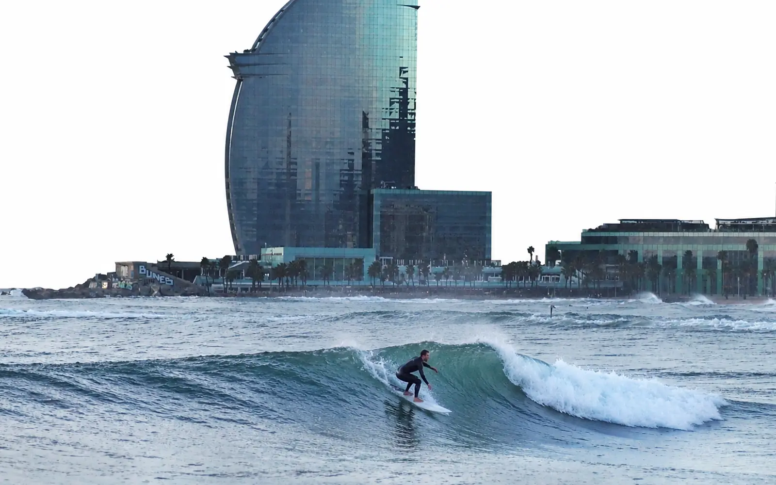 Surfista en una ola frente al Hotel Vela de la Barceloneta